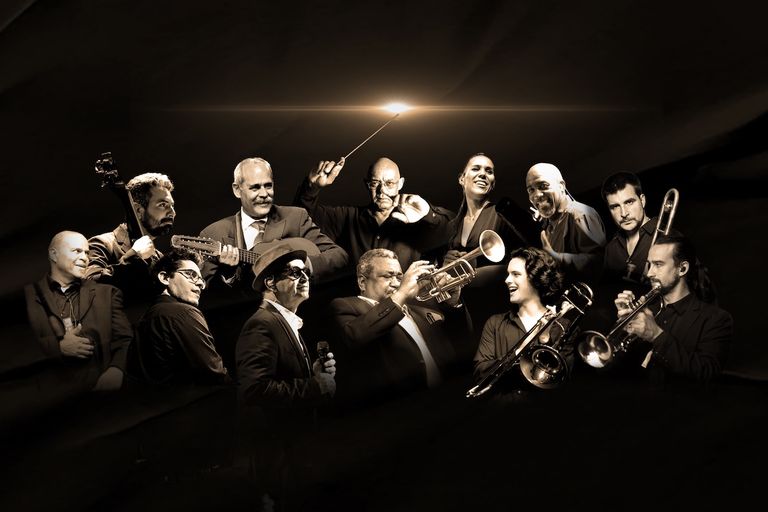 Cuban band Buena Vista All Stars posing together with musical instruments in sepia lighting.
